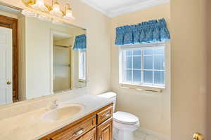 Bathroom with tile patterned floors, vanity, a shower with shower door, toilet, and ornamental molding