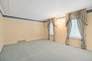 Unfurnished room featuring carpet flooring, visible vents, and plenty of natural light