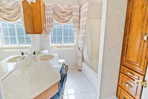 Bathroom with tile patterned floors, vanity, shower / bathtub combination with curtain, and a healthy amount of sunlight