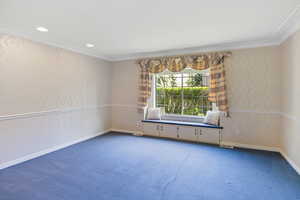 Unfurnished room featuring carpet, crown molding, and baseboards