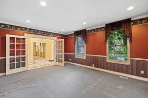 Empty room featuring wainscoting, french doors, visible vents, and carpet