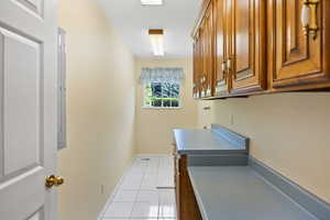 Laundry area with cabinet space, baseboards, and light tile patterned floors