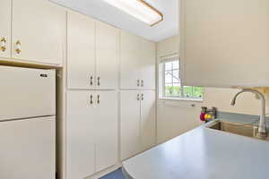 Kitchen with light countertops, freestanding refrigerator, and a sink