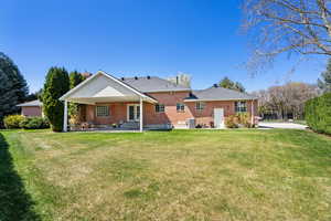 Back of property featuring brick siding, a yard, french doors, and a patio area