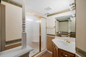 Bathroom with a shower stall, visible vents, and vanity