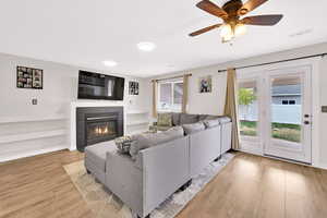 Living room with a tiled fireplace, visible vents, light wood finished floors, and a healthy amount of sunlight