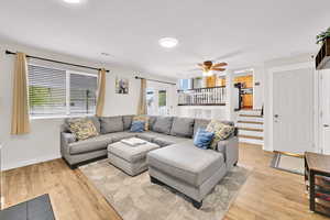 Living room featuring baseboards, a ceiling fan, visible vents, and light wood-style flooring