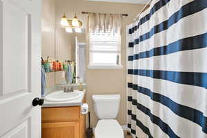 Full bathroom with a shower with shower curtain, toilet, and vanity