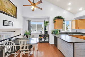 Kitchen featuring high vaulted ceiling, light brown cabinets, a ceiling fan, a sink, and wood-type flooring