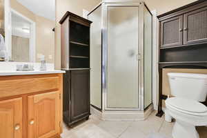 Full bath with a shower stall, toilet, vanity, and tile patterned floors