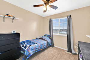 Bedroom featuring ceiling fan, baseboards, and carpet