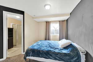 Bedroom with light colored carpet, visible vents, and light tile patterned floors