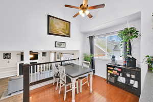 Dining room with wood finished floors, a towering ceiling, baseboards, and ceiling fan