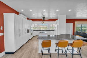 Kitchen featuring white cabinets, white fridge, a kitchen island, and a wealth of natural light