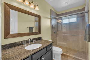 Full bathroom with tile patterned floors, vanity, a shower stall, and toilet