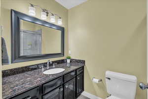Full bath with toilet, a shower with door, vanity, and baseboards