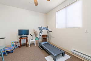 Exercise room featuring a baseboard heating unit, a ceiling fan, and carpet flooring