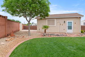 Rear view of house with a fenced backyard, a tile roof, a lawn, and stucco siding