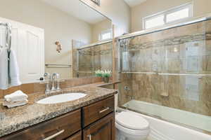 Bathroom featuring toilet, vanity, and shower / bath combination with glass door