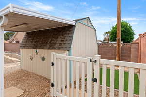 View of property exterior with a storage shed, a fenced backyard, and roof with shingles