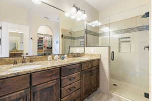 Full bath featuring a spacious closet, a shower stall, visible vents, and a sink