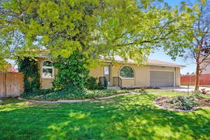 View of front of property with a front lawn, driveway, fence, brick siding, and a garage