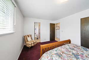 Carpeted bedroom featuring baseboards and connected bathroom