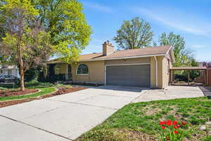 Ranch-style house with brick siding, an attached garage, a chimney, and concrete driveway