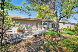 Rear view of property with a yard, fence, and a deck