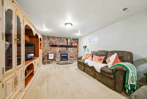 Carpeted living room with visible vents and a fireplace