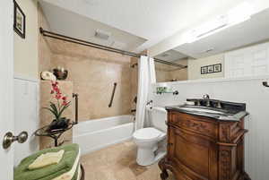 Bathroom with a wainscoted wall, toilet, visible vents, shower / tub combo, and vanity
