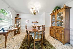 Dining room featuring wainscoting, an inviting chandelier, and crown molding