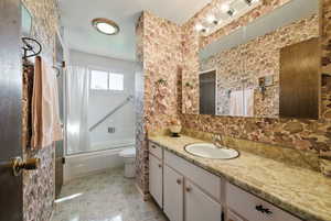 Bathroom featuring vanity, bath / shower combo with glass door, and toilet
