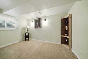 Carpeted empty room with baseboards, a textured ceiling, and visible vents