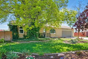 Obstructed view of property with an attached garage, brick siding, fence, and a front yard