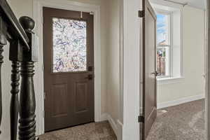 Doorway to outside with baseboards, carpet flooring, and plenty of natural light