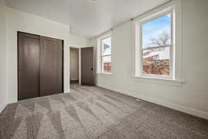 Unfurnished bedroom with carpet, a closet, and baseboards