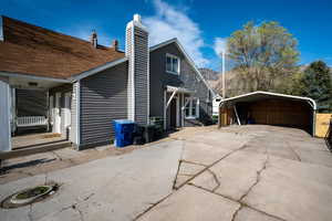 View of side of home featuring a chimney, driveway, and a carport