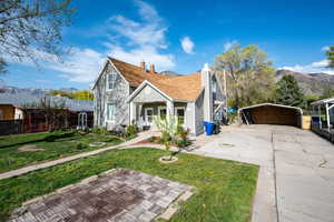 Bungalow-style house with a front lawn, a carport, a porch, a chimney, and concrete driveway