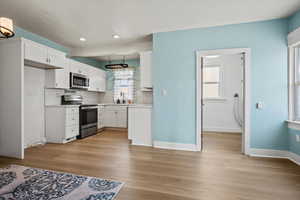 Kitchen featuring stainless steel appliances, light countertops, backsplash, and white cabinetry
