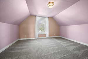Bonus room with baseboards, vaulted ceiling, carpet flooring, and a textured ceiling