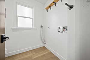 Laundry room featuring baseboards, light wood-style floors, washer hookup, electric dryer hookup, and laundry area
