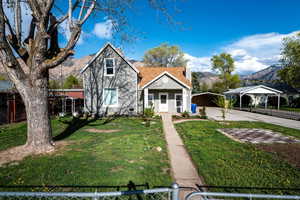 View of front of property with fence private yard, a detached carport, a front lawn, and a mountain view