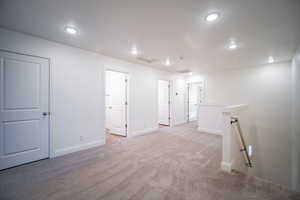 Below grade area featuring light carpet, baseboards, visible vents, and recessed lighting