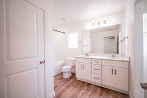 Full bathroom featuring wood finished floors, a sink, double vanity, and toilet