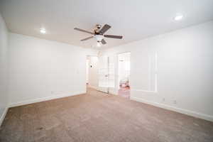 Unfurnished bedroom with light colored carpet, baseboards, ensuite bathroom, and recessed lighting