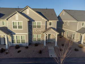 Townhome / multi-family property featuring stone siding and a patio area