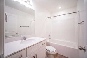 Bathroom with washtub / shower combination, wood finished floors, toilet, and vanity