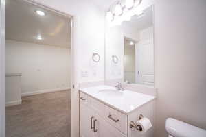 Half bath featuring recessed lighting, visible vents, toilet, vanity, and baseboards
