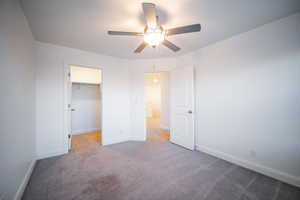 Unfurnished bedroom featuring baseboards, a ceiling fan, carpet flooring, and a spacious closet